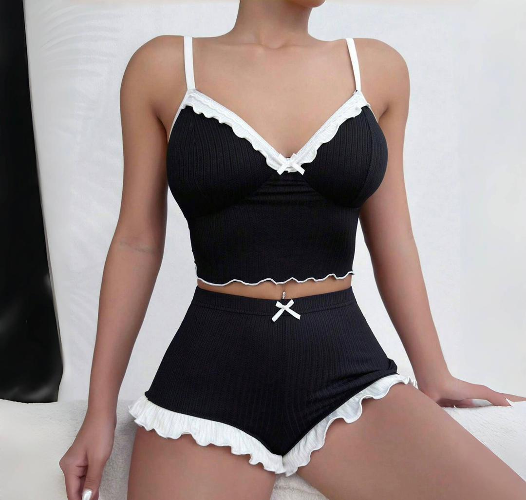 The Aria Romantique black lounge set with white ruffle trim and bow accents, offering a flirty and feminine look. Seductress Beauty nightwear.